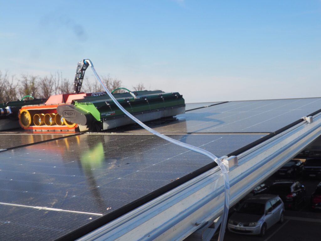 Robot de nettoyage NRI OPTI+ projetant de l'eau osmosée sur des panneaux photovoltaïques en ombrière